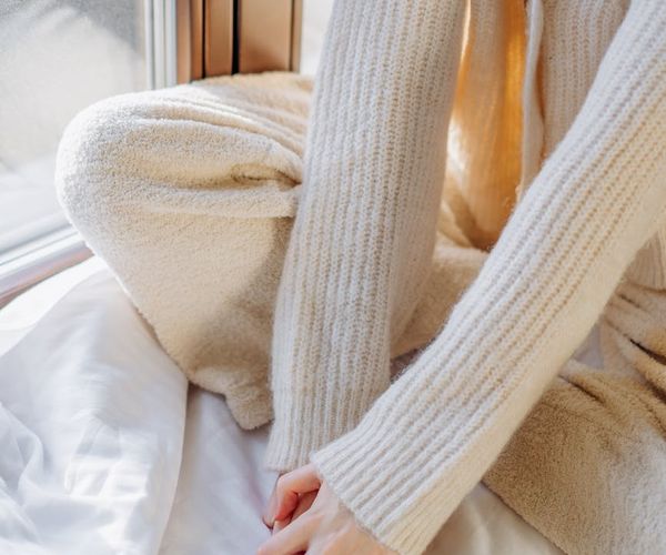 Person stretching peacefully by a window with soft morning light.